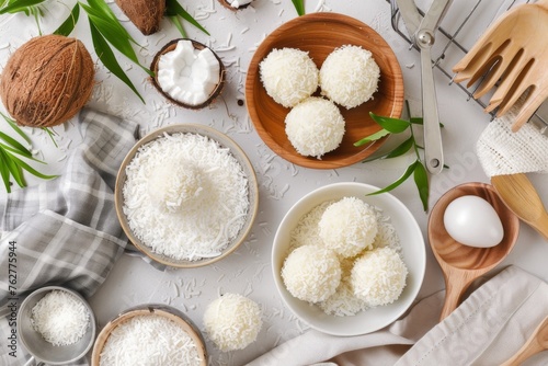 White kitchen table with coconut balls freshly made with bowl with grated coconut and kitchen tools. Top view. Horizontal composition. photo