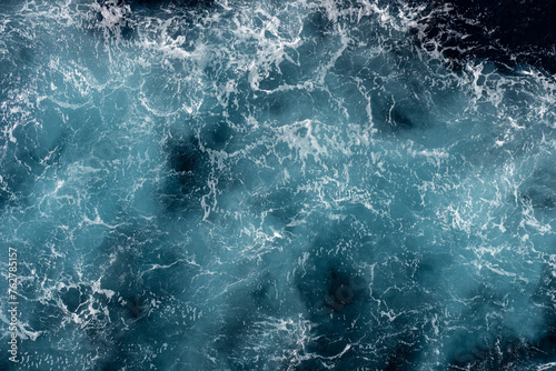 Aerial view of the tumultuous ocean with waves creating intricate patterns on the water's surface