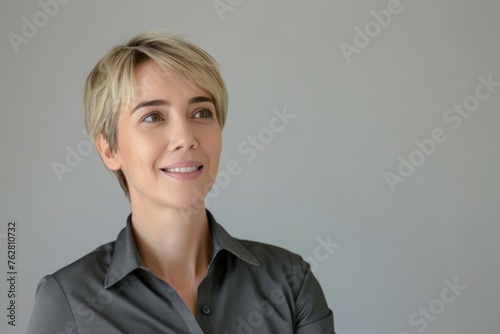 A woman with short blonde hair is smiling and looking up at the camera