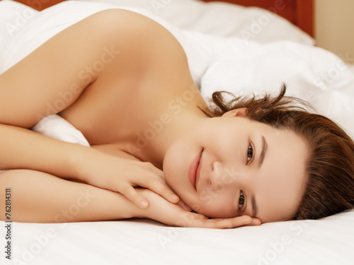 Good morning Attractive young woman smiling and looking at camera while lying in the bed at home 