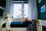 window in a coloured teenager room with green walls and white bead in a bright day 
