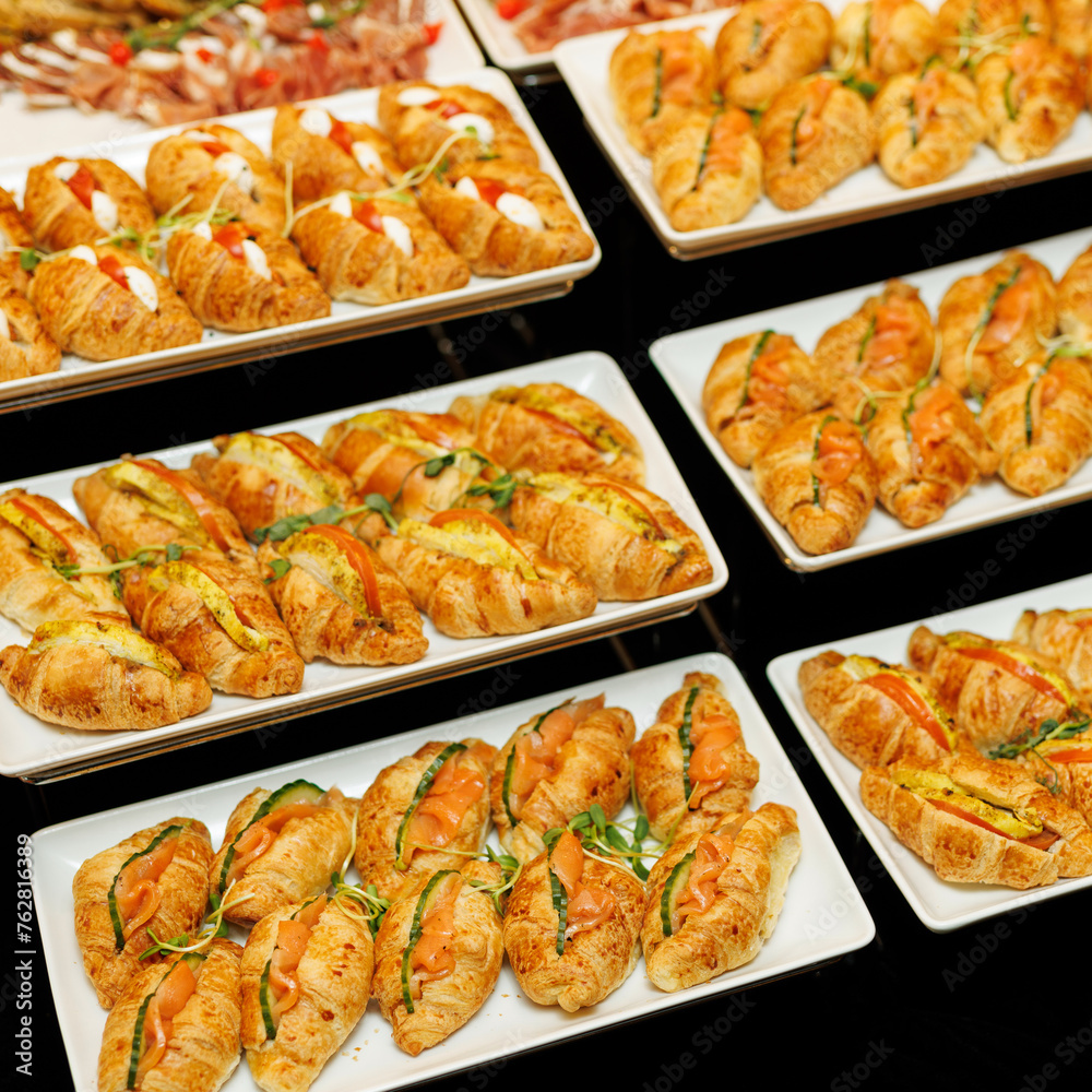 A lavish spread of gourmet appetizers, featuring golden croissants garnished with fresh herbs and a variety of delicious fillings.