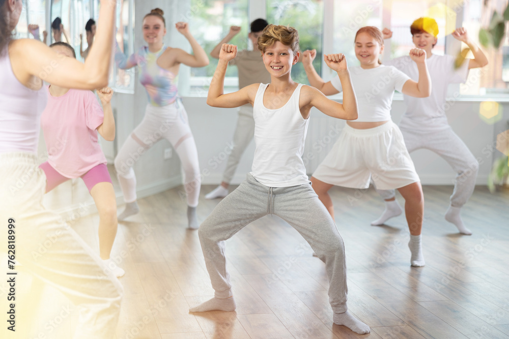 Fototapeta premium Female teacher performs choreographic exercises and teaches energetic mobile social house dance together with teenagers