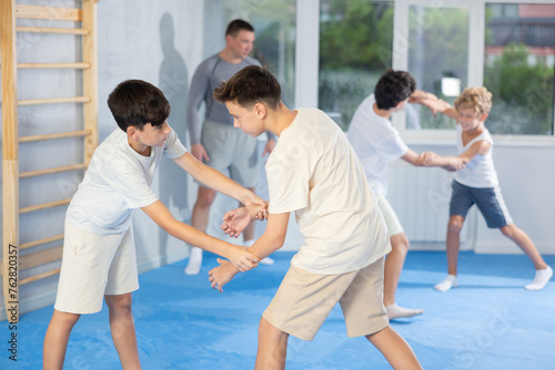 Young children working in pair mastering new self-defense moves at modern gym