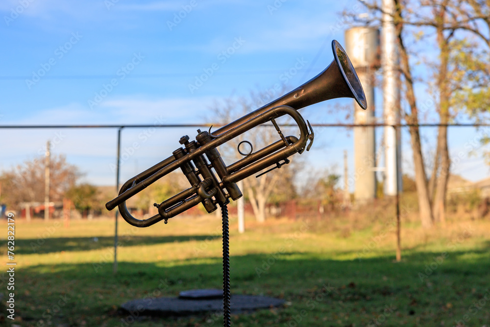 A brass instrument is on a pole in a park