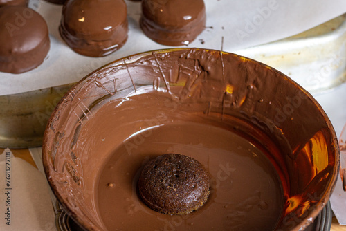 Bolo saboroso e fresco mergulhado no chocolate quente derretido pronto para ser banhado