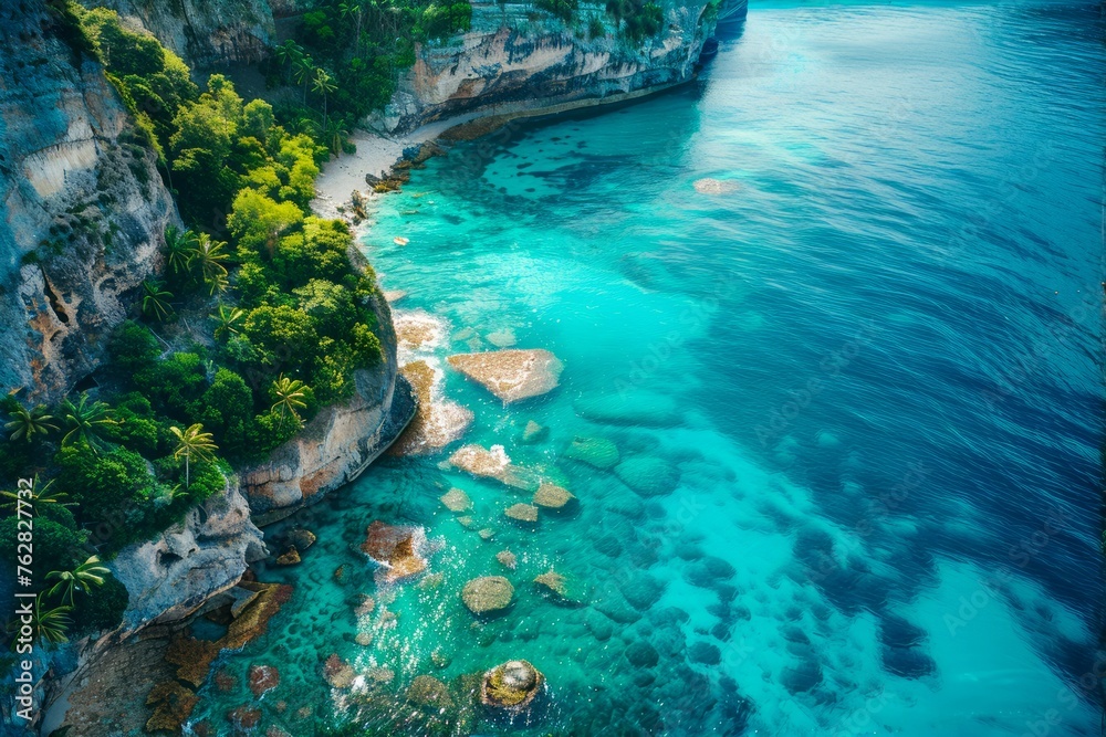 Serene Tropical Coastline with Clear Blue Waters, Lush Cliffside Vegetation, and Rocky Beach