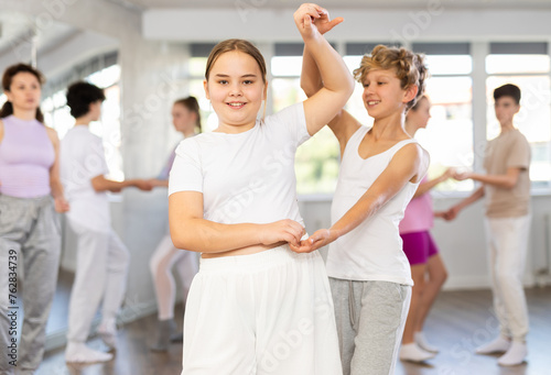 Group of teenagers, girls and boys, dance a slow ballroom dance in a choreography studio