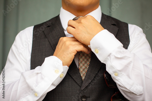 Man in grey suit vest with yellow plaid tie dressing detail closeup
