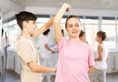 Teen girl paired with guy practices movements of waltz dance and trains to perform movements during lesson in choreography studio.