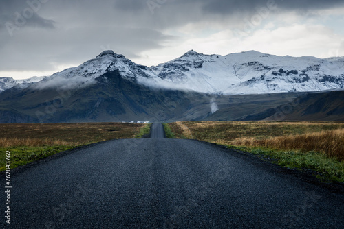 Road leading towards the snow-capped mountains during the cloudy day in Iceland countryside