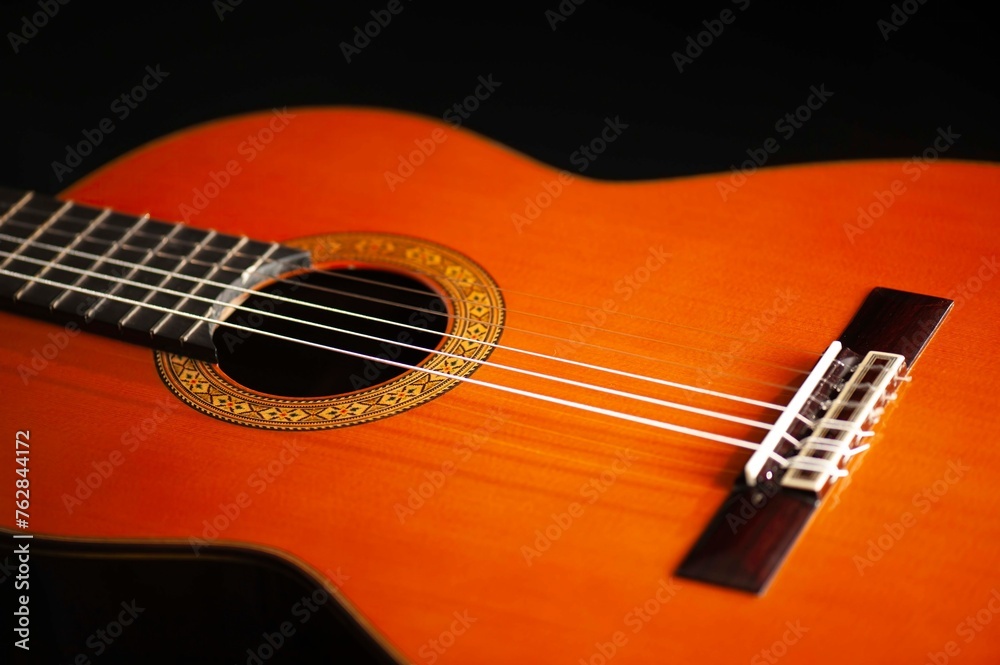 Fototapeta premium Classical Spanish flamenco guitar close up, dramatically lit isolated on black background with copy space.