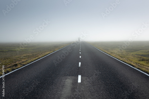 Car driving on the straight into the distance in the mist in the Icelandic country road