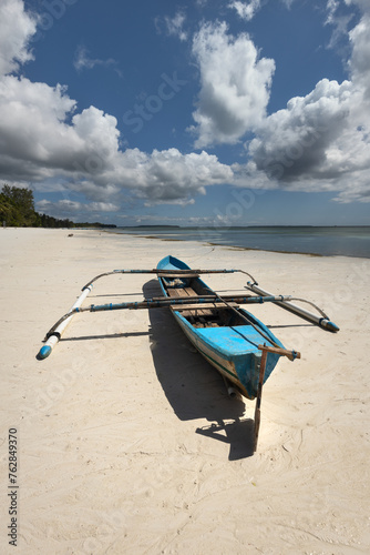 Small fishermens' canoe boat at the Ngurbloat white sand beach in Kei Islands, Maluku during bright sunny day and blue skies