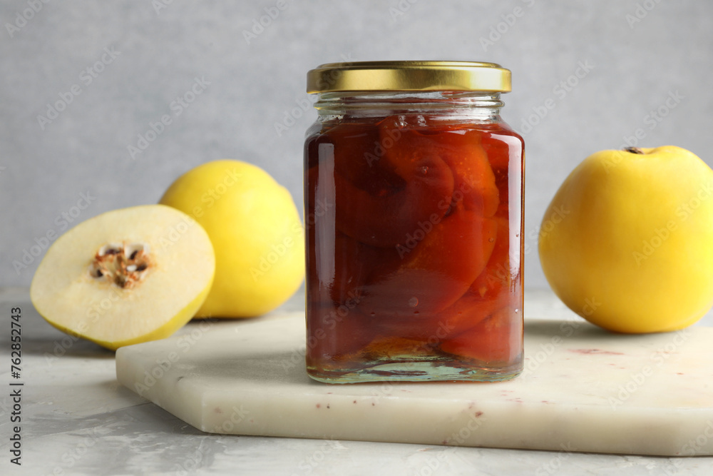 Tasty homemade quince jam in jar and fruits on grey textured table, closeup Tasty homemade quince jam in jar and fruits on grey textured table, closeup