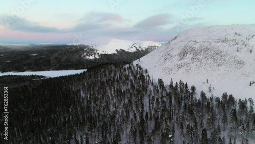 Aerial view passing the snowy Kellostapuli fell, toward Kesankitunturi, sunset in Lapland photo