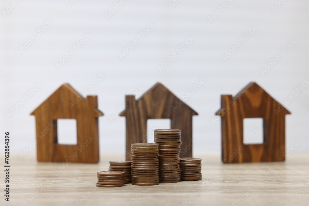 House models and stacked coins on wooden table House models and stacked coins on wooden table