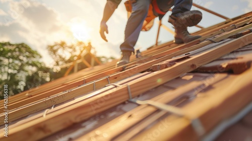 Close up of roof worker building a wood structure house construction on roof in background of shining. Construction concept of success or achievement.