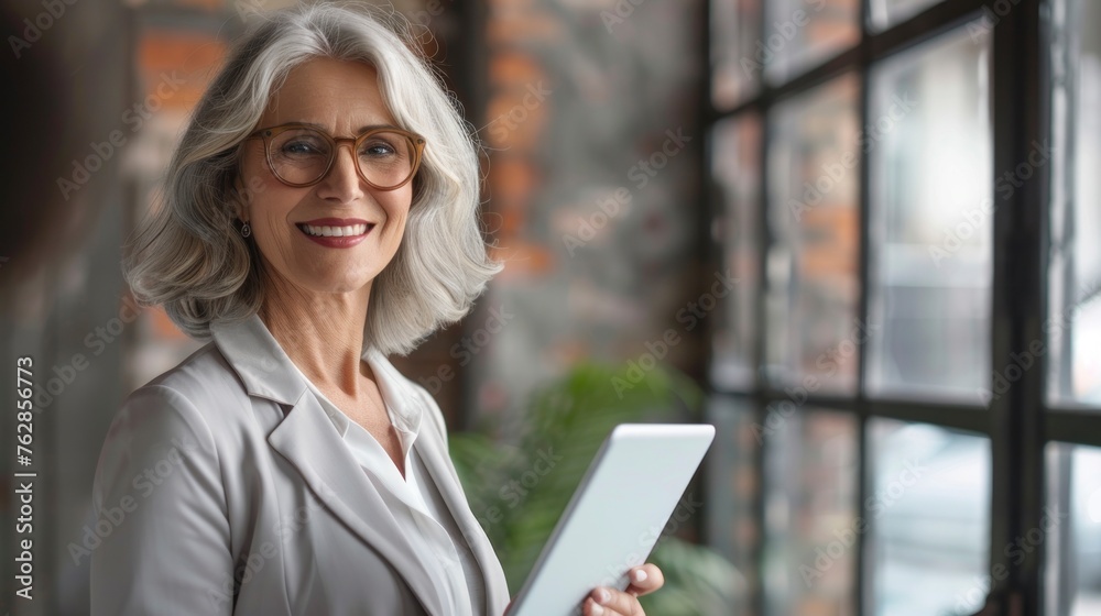 beautiful senior woman in executive suit using a tablet in a modern daytime office