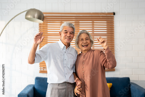 Portrait of Asian senior elderly couple standing in living room at home. 