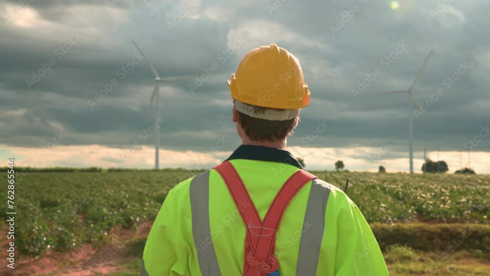 Engineer is walking in a field wearing a protective helmet on head Engineer is walking in a field wearing a protective helmet on head