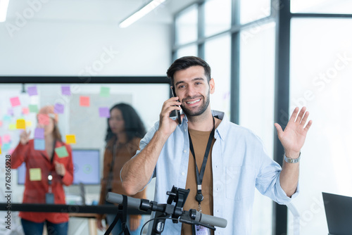 Portrait of smiling businessman talking on mobile phone while colleague using scooter in office