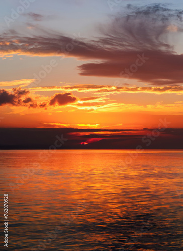 Sunset sky with reflections in water, sunlight and colored orange clouds © ROKA Creative
