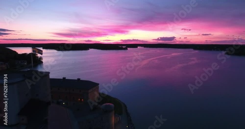 Aerial: Vaxholm Castle Under A Spectacular Pink Sky, The Calm Baltic Sea Reflects The Vibrant Sunset, Highlighting Sweden'S Maritime Heritage - Stockholm, Sweden photo