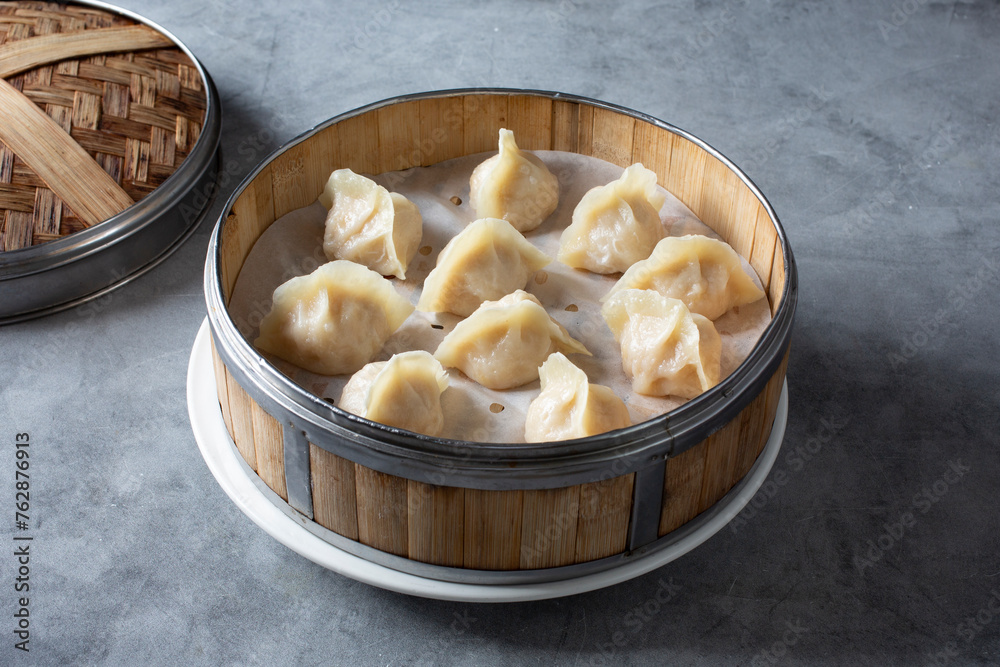 A view of several steamed dumplings inside a bamboo steamer basket. A view of several steamed dumplings inside a bamboo steamer basket.