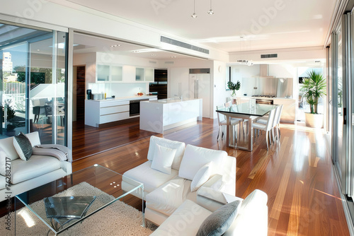 Modern open plan home interior with kitchen  dining room and living area featuring glass sliding doors leading to a wooden floor deck in Sydney  Australia