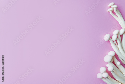 Cluster of white enoki mushrooms on a pastel pink background with space for text, ideal for vegan or healthy food concepts