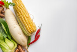 Assorted fresh vegetables including corn, red chili, and bok choy with copy space on white background, ideal for healthy eating and vegetarian concepts