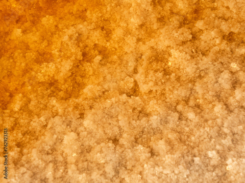 Solar salt lake. Salt crystals (salt grain) in hypersalted lake. Self-seeding salt. Water in reservoir is salmon colored and red because of abundance of halotolerant bacteria Dunaliella salina. photo