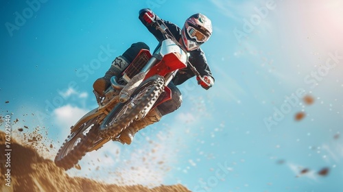 Motocross rider in midair against clear blue sky, displaying skill and precision