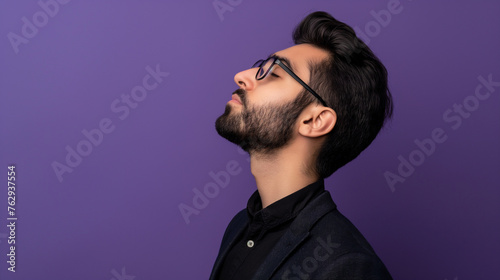 Profile view of young handsome Persian businessman with glasses looking up on purple color background professional photography