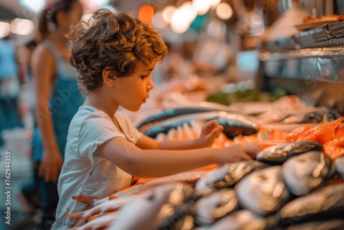 Curious Young Boy Gazing in Awe at Colorful Fresh Fish Laid out in Vibrant Fish Market Stall with Busy Fishermen Engaged in Selling Activities, Creating a Captivating Scene of Traditional Market Life.