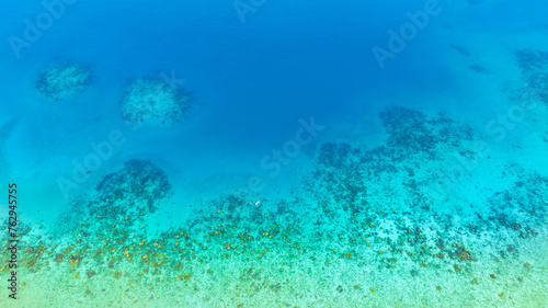 Top view. Summer sea water  blue surface. The water is clear with ripples and sparkles in the sunlight and you can see coral under the sea.