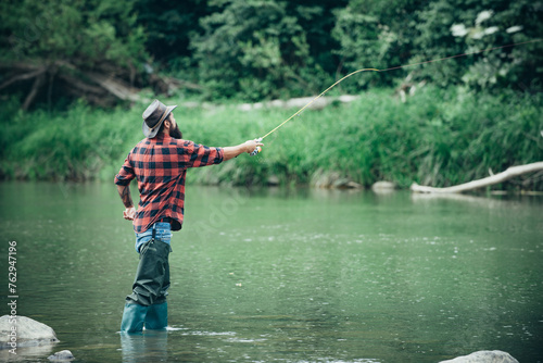 Man with fishing rod, fisherman men in river water outdoor. Summer fishing hobby. Man pulling fishing rod.