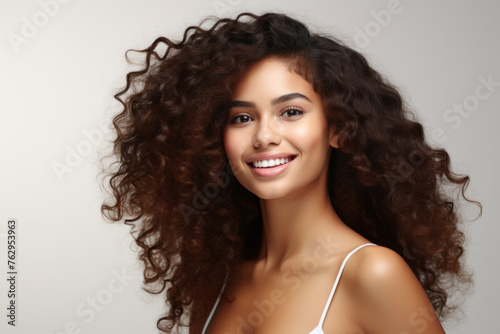A woman with curly hair is smiling and looking at the camera