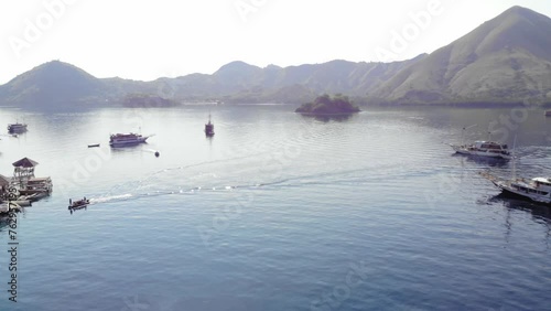 tourist boats at Pulau Kelor island in Indonesia in Komodo national Park. shot from a drone, offering a stunning aerial perspective of the marine beauty and mountains in the background. photo