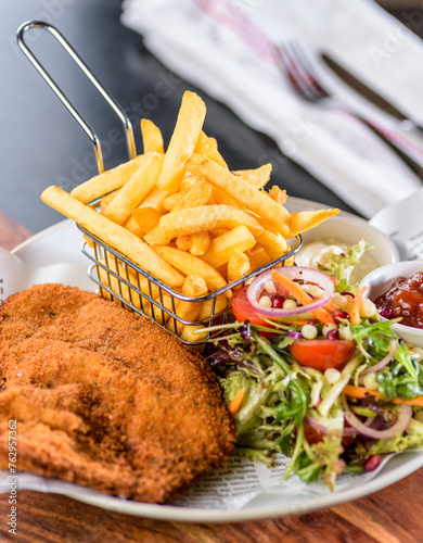 A serving of grilled veal schnitzel, with french fries and green salad