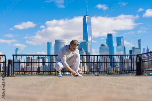 Sportsman tying sneakers. Athletic shoes. Fitness man tie shoelaces outdoor. Fitness man tying lace of sports shoes. Athlete getting ready for workout wearing shoes sitting on floor. Start training