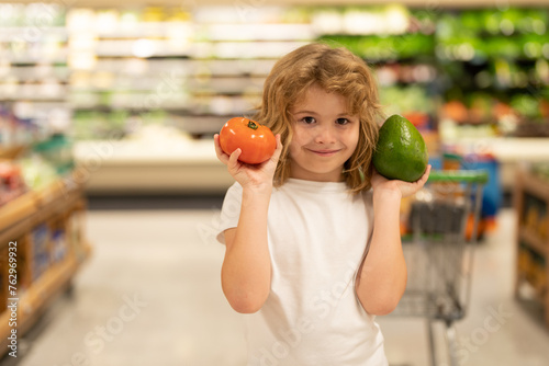 Child choosing vegetables in food store. Kids in food market. Sales, discounts in food market store and shopping. Cute boy in market hold vegetables and fruits. Child shopping in market store.