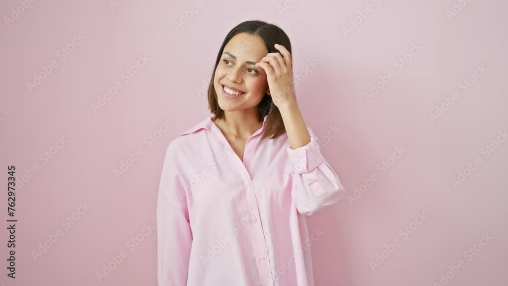 Confidently beautiful and relaxed, a young hispanic woman with a natural smile poses side-profile wearing a shirt. she stands against a pink, isolated background, exuding trust and cheer. Confidently beautiful and relaxed, a young hispanic woman with a natural smile poses side-profile wearing a shirt. she stands against a pink, isolated background, exuding trust and cheer.