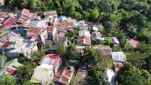 Aerial birds eye shot of poor Neighborhood with rusty roof in tropical suburb of Dominican Republic. Sunny day with palm trees on Hispaniola island.