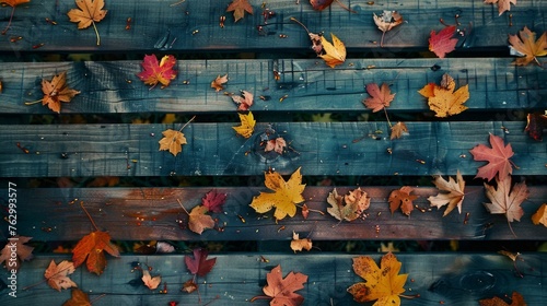 Colorful fallen autumn leaves scattered on old, weathered wooden planks outdoors.