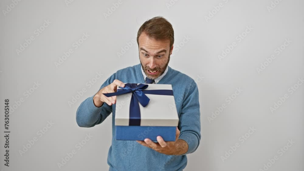 Astonished middle-aged hispanic man with an open mouth, holding a gift in disbelief, experiencing a mix of fear and amazement on an isolated white background Astonished middle-aged hispanic man with an open mouth, holding a gift in disbelief, experiencing a mix of fear and amazement on an isolated white background