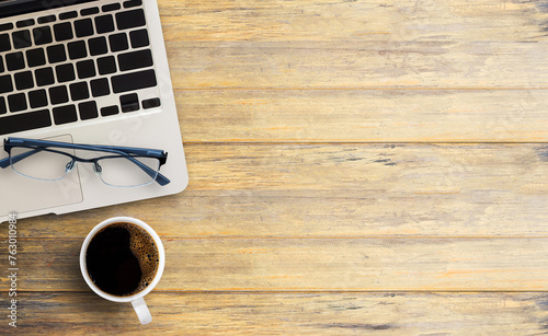 Laptop computer and glassesl with cup of coffee on wooden table photo