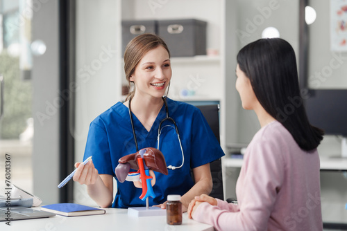 Caucasian liver professional female doctor explain to asian female patient using human liver model at desk in medical room, Liver cancer and Tumor, Jaundice, Viral Hepatitis A, B, C, D, E, cirrhosis