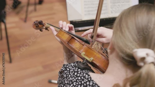 A moving slow motion shot of a musician playing a violin or viola by using the pizzicato technique during a classical symphony orchestra rehearsal